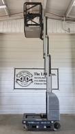 Gray JLG 20MVL vertical mast lift, stowed, side view with platform and battery cover