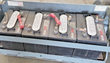 Four batteries wired in series on the scissor lift's pull-out battery tray, red terminal boots and lugs