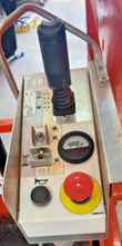 Platform control console: joystick with function decals, toggle switches, battery charge gauge, red emergency stop
