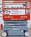 Skyjack SJIII 3219 side profile, lowered: orange platform with control box, gray scissor stack and solid tires