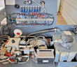 Open control compartment: relay and terminal board with wiring harness above the hydraulic valve manifold and pump