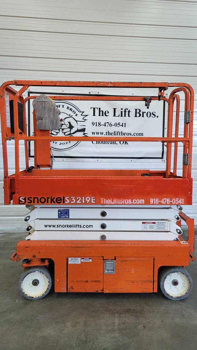 Orange and white Snorkel S3219E electric scissor lift, stowed, side view