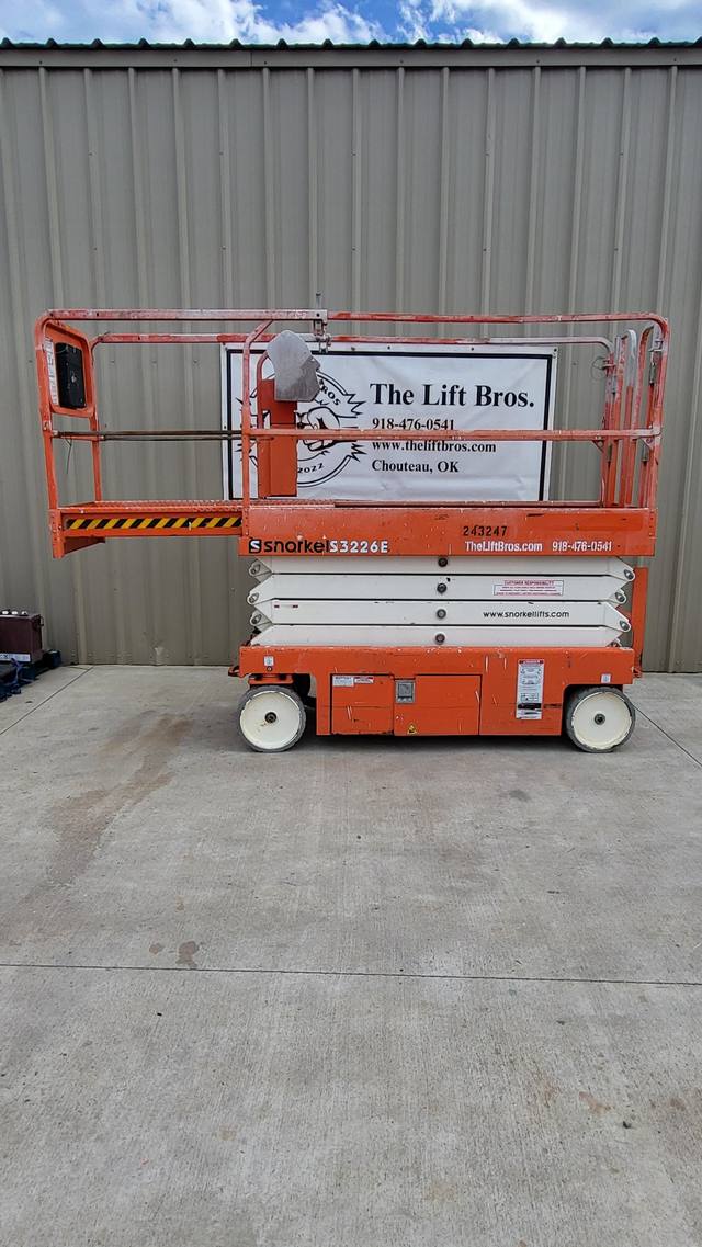 2020 Snorkel S3226E electric scissor lift, stowed, side view in front of the Lift Bros sign
