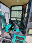 MH13RX mini excavator: open cab door showing the pilot joystick, black seat, switch console and clip-on cab fan