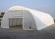 White PVC fabric arch building with the end door open, steel arch trusses visible inside