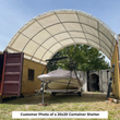 Boat on a trailer parked under a white fabric shelter spanning two yellow shipping containers