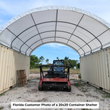 White arched shelter between two tan containers with a red tracked skid steer and mulcher at the open end