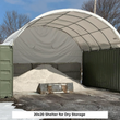 White arched shelter between two green containers with a pile of loose material and a loader bucket inside