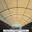 Looking down the inside of a single-pipe container shelter, galvanized arch ribs under a tan cover between two containers