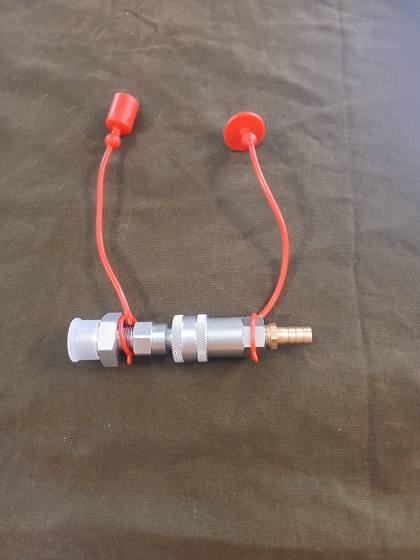 Hydraulic tank quick-connect drain, coupled halves with red dust caps and brass hose barb