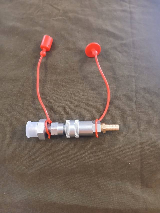 Hydraulic tank quick-connect drain, coupled halves with red dust caps and brass hose barb