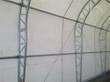 Galvanized steel dual truss arches and purlins seen inside the fabric building, supporting the white PVC cover