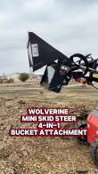 4-in-1 bucket's clamshell jaw open over a mulch pile, title text 'Wolverine Mini Skid Steer 4-in-1 Bucket Attachment'
