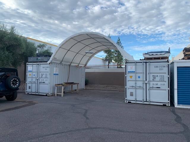 White dome-roof shelter spanning two light blue-green shipping containers