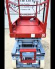 Skyjack scissor lift red diamond-plate platform deck with chain entry gate and ground control panel below