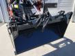 4-in-1 bucket head-on from the front, empty bucket floor, sleeved hoses across the top and quick-attach arms
