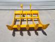 Yellow rake from behind: cross tubes, twin mounting lugs and five tine tips over a serrated edge