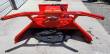 Red disc mulcher from the rear: push frame arms, hydraulic couplers and the toothed cutting disc beneath