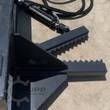 Tree and post puller jaws up close: serrated steel gripping teeth on both arms with the hydraulic cylinder behind
