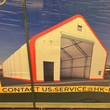Crate artwork of a white dual-truss fabric building with red trim and open roll-up door