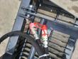 Two hydraulic quick couplers with red dust caps mounted on the rock grapple frame above the steel tines