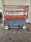 Orange and gray Skyjack SJIII 3226 scissor lift, side view, lowered, worn paint and rust on platform