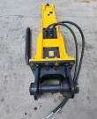 TOFT750 breaker from above: bolted valve plates, caution decal, black mounting bracket with pin and hoses