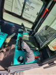 MH13RX mini excavator cab: twin pilot joysticks, plastic-wrapped operator seat and checker-plate floor