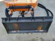 Stump grinder's black universal skid steer quick-attach plate, orange body and sleeved hydraulic hoses behind it