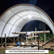White dual-truss fabric shelter lit at night over a small floatplane on wooden supports; caption: personal aircraft cover