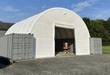 White PVC container shelter spanning two gray shipping containers, front winch door open, lift inside
