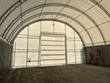Interior of the container shelter: arched steel dual-truss frame, white PVC cover and end wall door