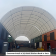 Inside a large white arched shelter between stacked shipping containers; caption: four 40x40 shelters back to back
