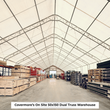 Warehouse interior of a white dual-truss building filled with crates and pallets