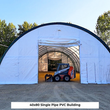 White single-pipe arched PVC building with an open front door and a skid steer parked inside