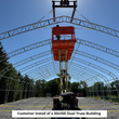 Boom lift raising a worker inside a dual-truss frame during building installation