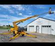 Yellow Haulotte 3632T towable boom lift, boom extended and work platform raised, outriggers set