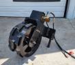 Black steel trench compaction wheel with welded cleats, hydraulic motor, quick-attach mount plate and hoses