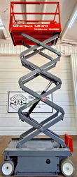 Red Skyjack SJIII S3219 scissor lift extended to full height, gray scissor stack raised