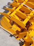 Yellow excavator buckets and attachments from the CAT 301 package, stacked with pin bores showing