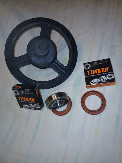 Timken bearings and two red-brown oil seals beside a spoked track idler wheel from a mini skid steer