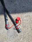 Two hydraulic hoses with red-capped quick couplers, one cap unplugged
