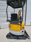 ME20 mini excavator from behind: yellow rear housing, black seat under the canopy frame, rubber tracks and blade