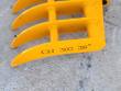 Yellow rake's outer tine bar stamped CAT 303 38 inch, tubular cross-braces above the curved tines