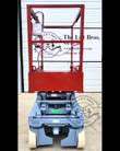 Skyjack scissor lift lowered: red platform with guardrails, upper control box and chain entry gate