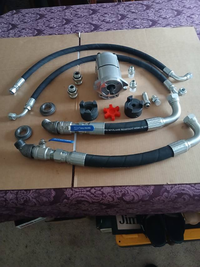 Hydraulic pump kit laid out: gear pump, lovejoy coupler, 1-inch suction hoses with ball valves, pressure hoses