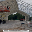 Dual-truss frame interior, white cover partly installed, worker on an orange scissor lift platform