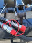 Grapple clamp cylinder rod end and clevis pin, with two red-capped hydraulic couplers below