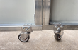 Swivel caster wheels bolted to the bottom rail of the workshop's sliding door panels