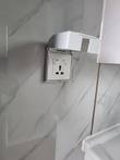 Wall-mounted universal power outlet with hinged splash cover on a marble-look wall